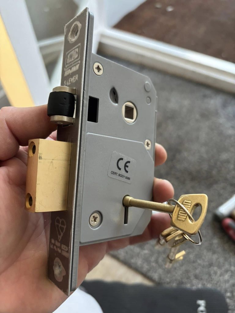 An image of a hand holding a Union sash lock case with the key in